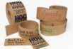 Collection of kraft paper custom tapes featuring printed brand names and logos, with a natural eco-friendly appearance.