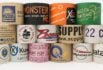 Stacked rolls of custom kraft and white tapes with various company logos and branding, showcasing a variety of styles and colors.