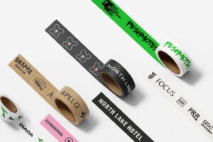 Flat-lay of multiple custom packaging tapes in black, white, and kraft colors, arranged in a diagonal layout with diverse branding