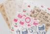 Premium custom food wrapping paper in five distinct designs, including kraft paper with botanical prints, translucent sheets with cherry patterns, bold pink burger icons, vintage newspaper layouts, and blue fast-food illustrations — ideal for upscale takeout and food branding.