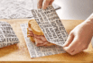 Premium custom food wrapping paper being used to wrap a fresh deli sandwich on a wooden surface, featuring bold, food-themed typography in black and white — ideal for enhancing takeout presentation and restaurant branding.