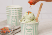 Hand sprinkling colorful toppings over a Sundae Lane mint chip ice cream cup.