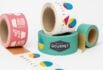 Group of custom tape rolls in vibrant colors and bold geometric patterns, showcasing branding for office and gourmet food services.