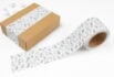 Decorative tape with floral patterns sealing a kraft box, paired with a matching roll of tape on a clean white background.