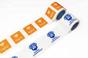 Two rolls of custom logo tape laid out side by side, one with an orange 
